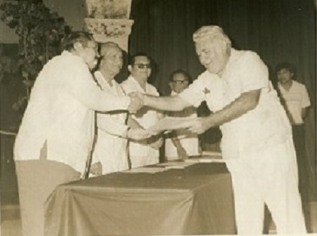 El poeta Luis Ortiz Martínez recibe un reconocimiento del suplemento Diálogo de manos de Raúl Maldonado Coello. Atestiguan Raúl Maldonado Cetina y don Oswaldo Baqueiro López. 18 de octubre de 1985.