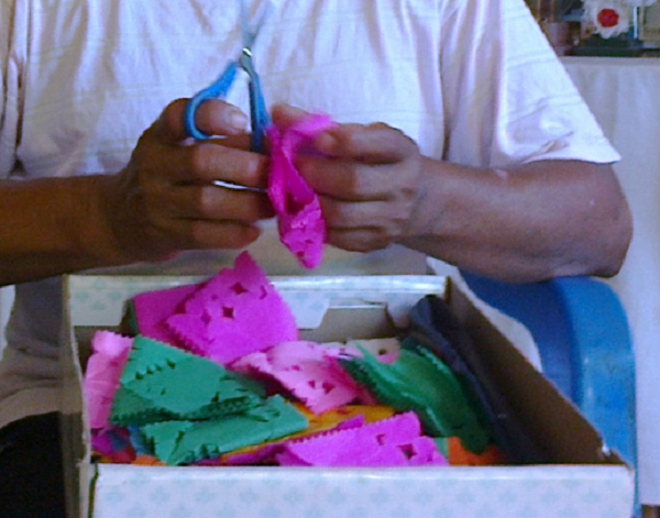 Cien banderines de papel picado se requieren para dar cuerpo y forma a los “ramilletes”. Detalle de la labor de corte y picado del “papel de china”.